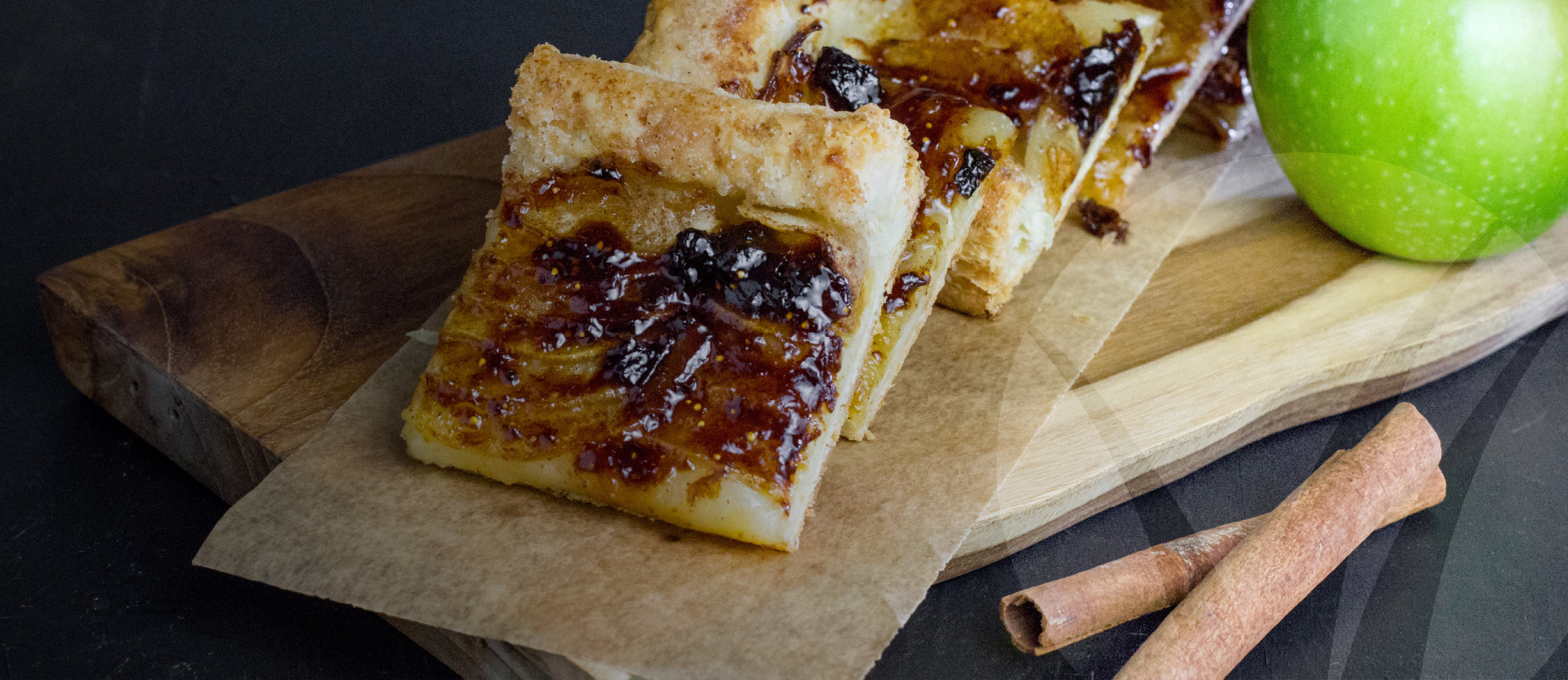 Sliced apple tart on a board alongside a fresh apple and cinnamon sticks. Better Homes and Gardens Real Estate