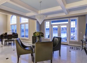 Formal dining or sitting room featuring large crystal chandelier, marble floors and piano; looking out onto the waterfront.