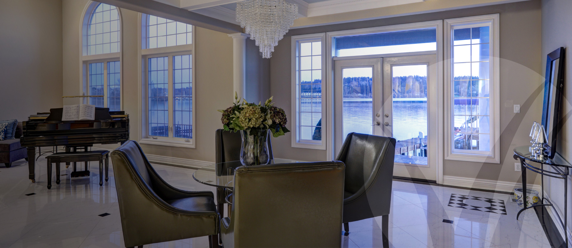 Formal dining or sitting room featuring large crystal chandelier, marble floors and piano; looking out onto the waterfront. Better Homes and Gardens Real Estate
