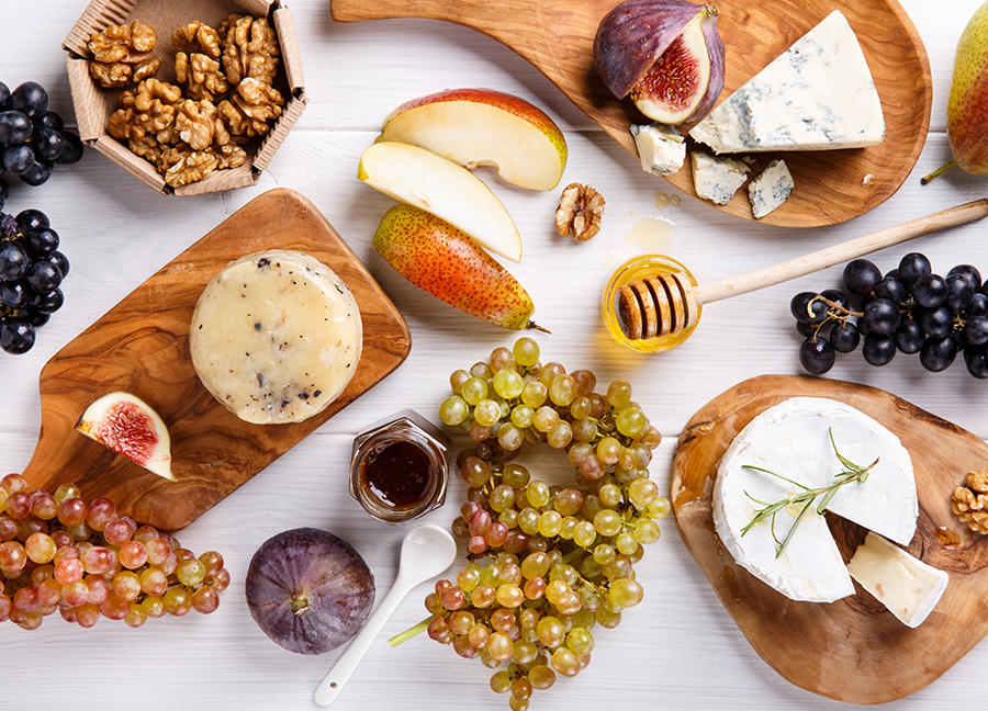 Cheese board with a variety of cheeses, fruits, nuts, and honey.