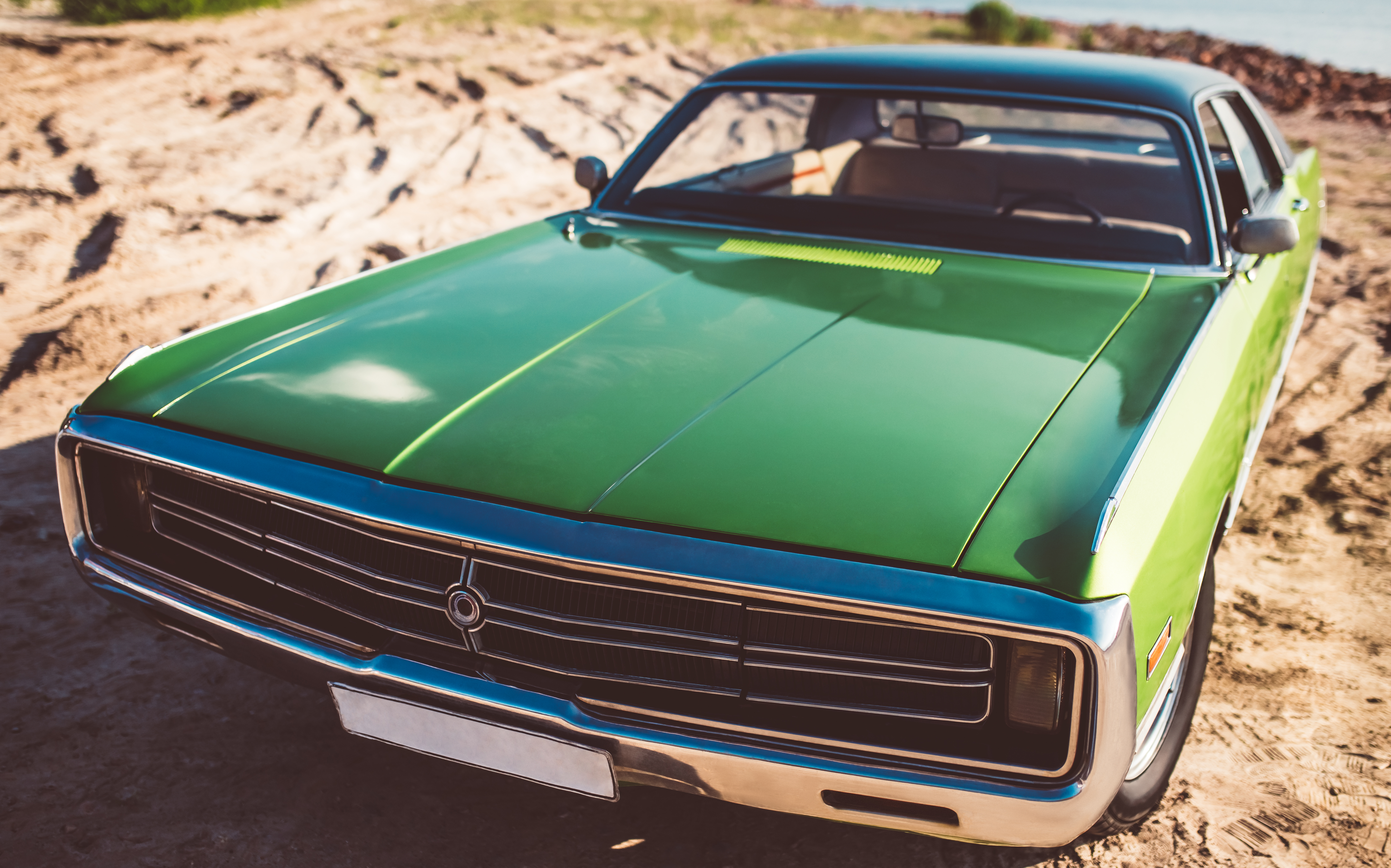 green muscle car parked in sand